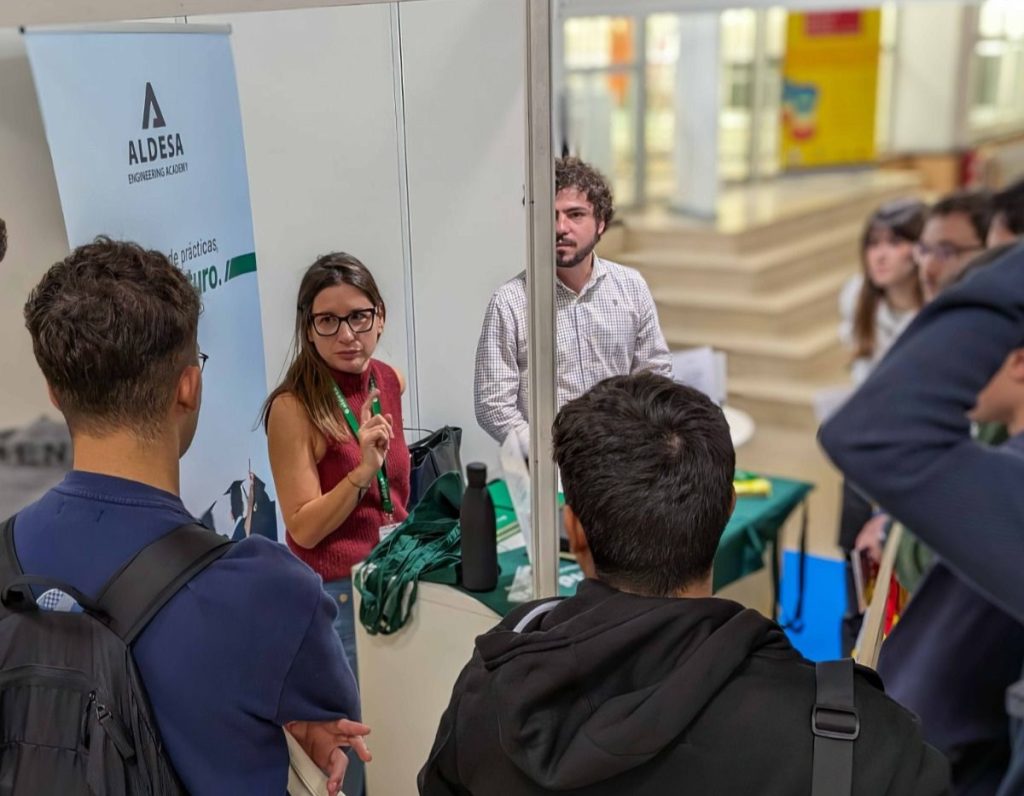 Estudiantes de ingeniería se interesan por la Aldesa Engineering Academy en el stand de una feria.